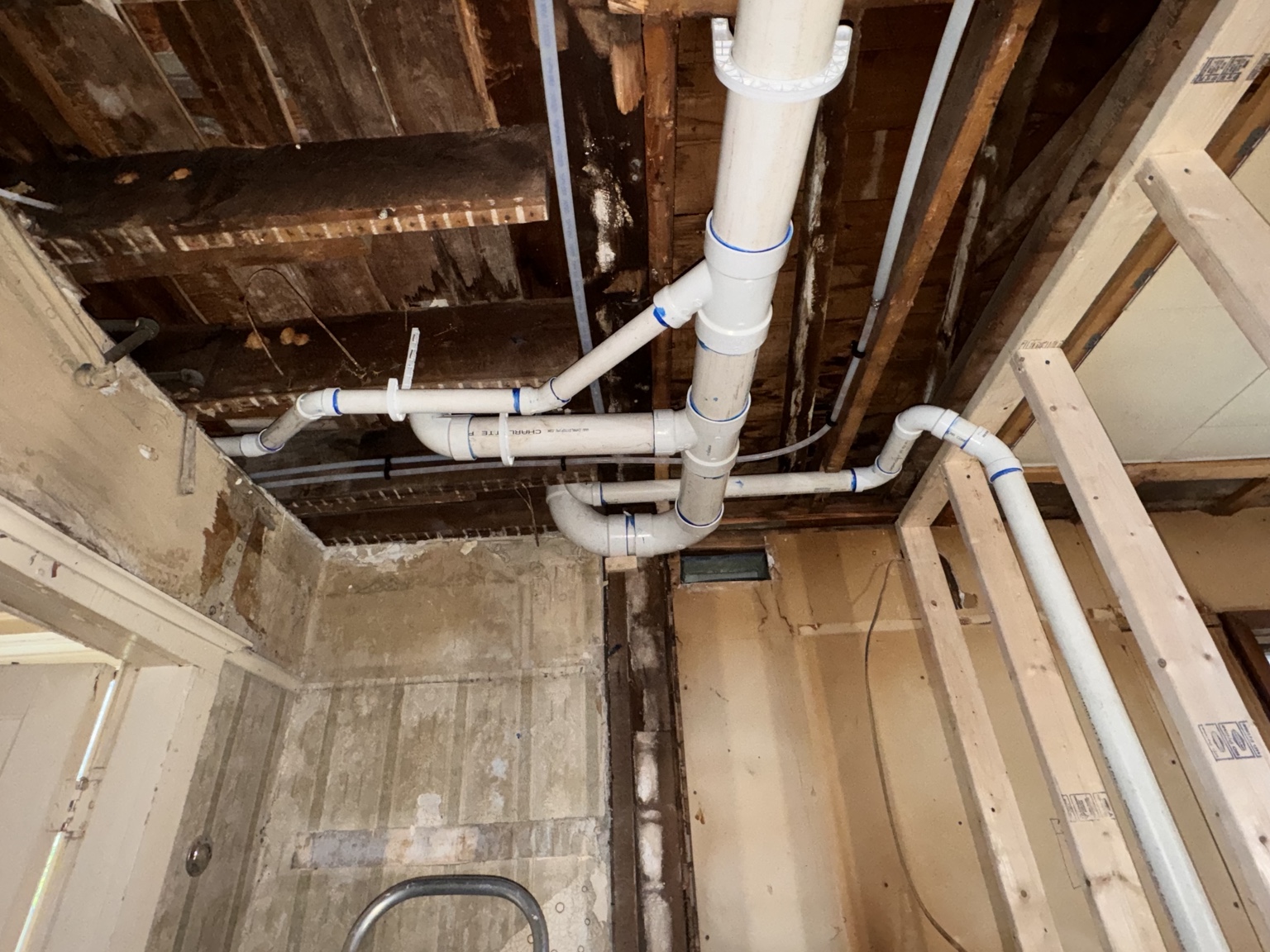 Exposed PVC drain, waste, and vent piping in open framing