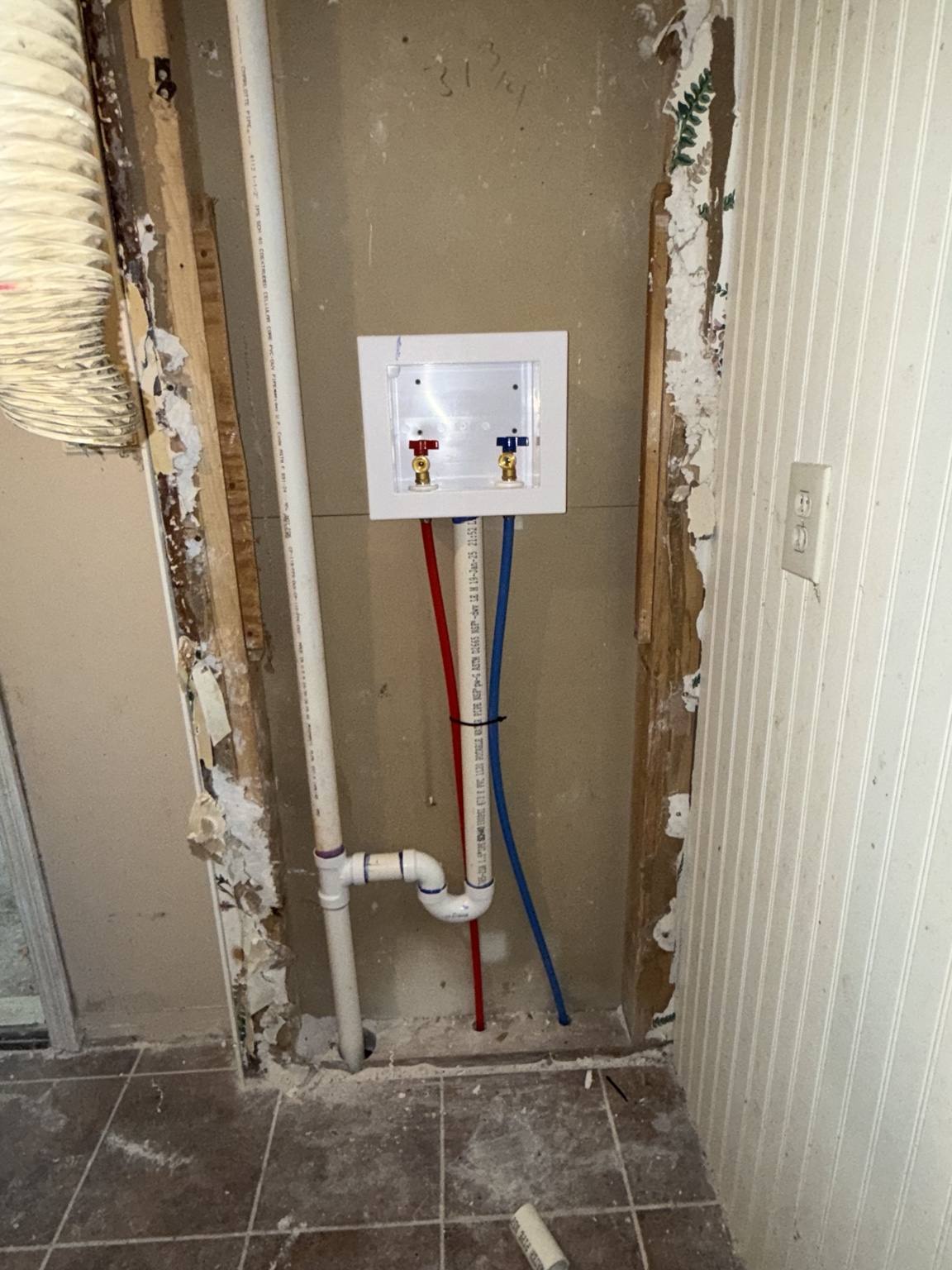 Laundry outlet box with red and blue water lines and PVC drain piping installed by AHVEE