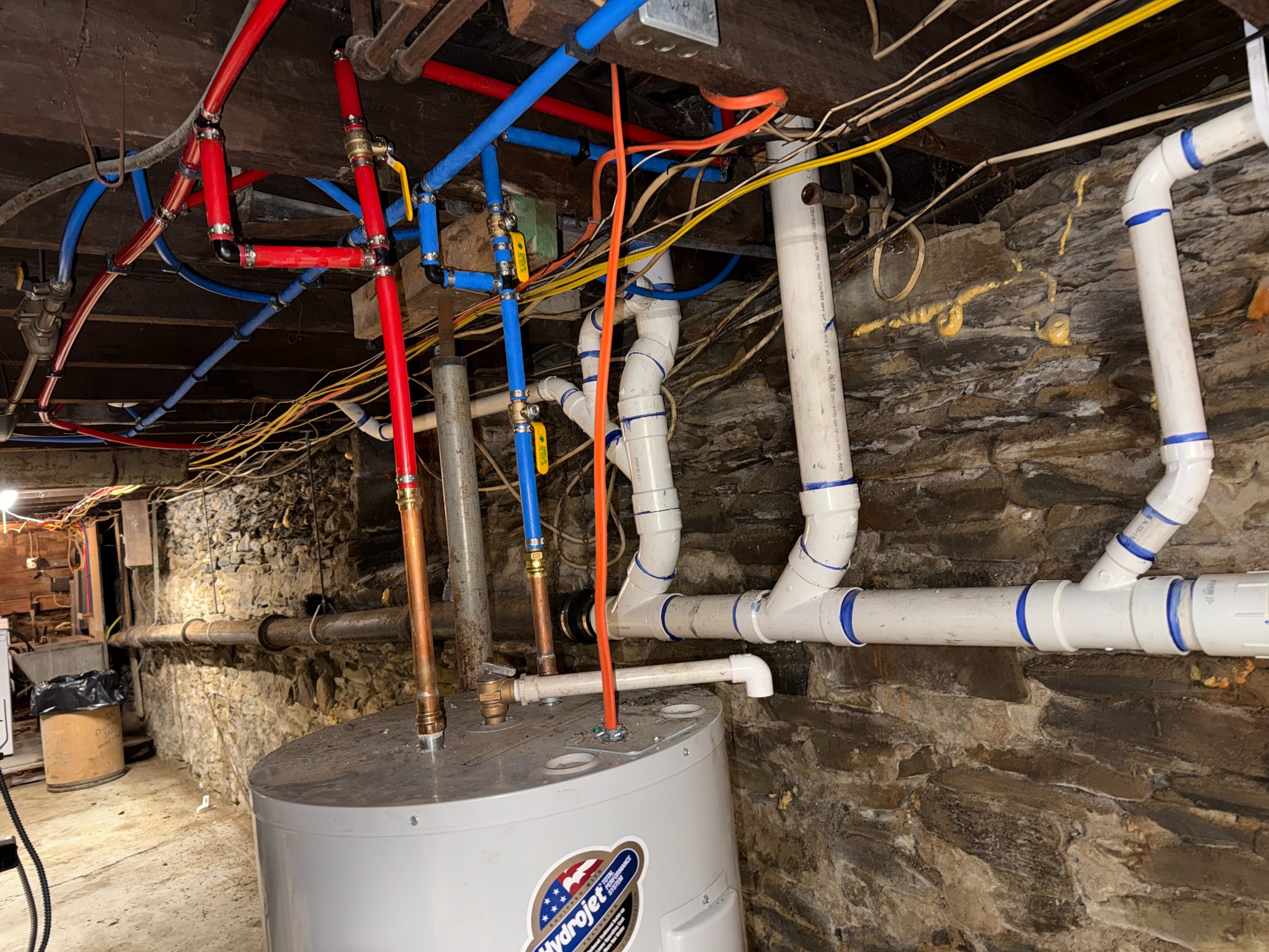 Red and blue PEX hot and cold domestic water piping installed by AHVEE in an open basement