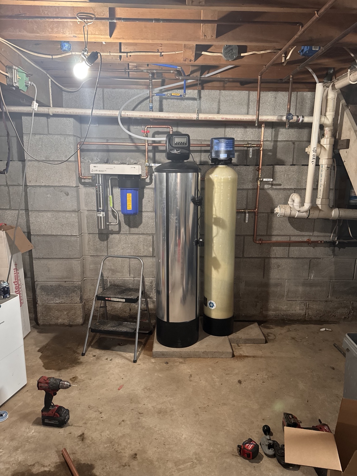 Water-treatment vessels, filter housing, controls, and connected copper piping installed in a basement